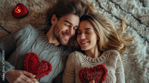Couple Lying with Red Hearts, Romantic Moment, Top view of a joyous young couple lying down surrounded by red paper hearts, sharing a moment of love and happiness photo