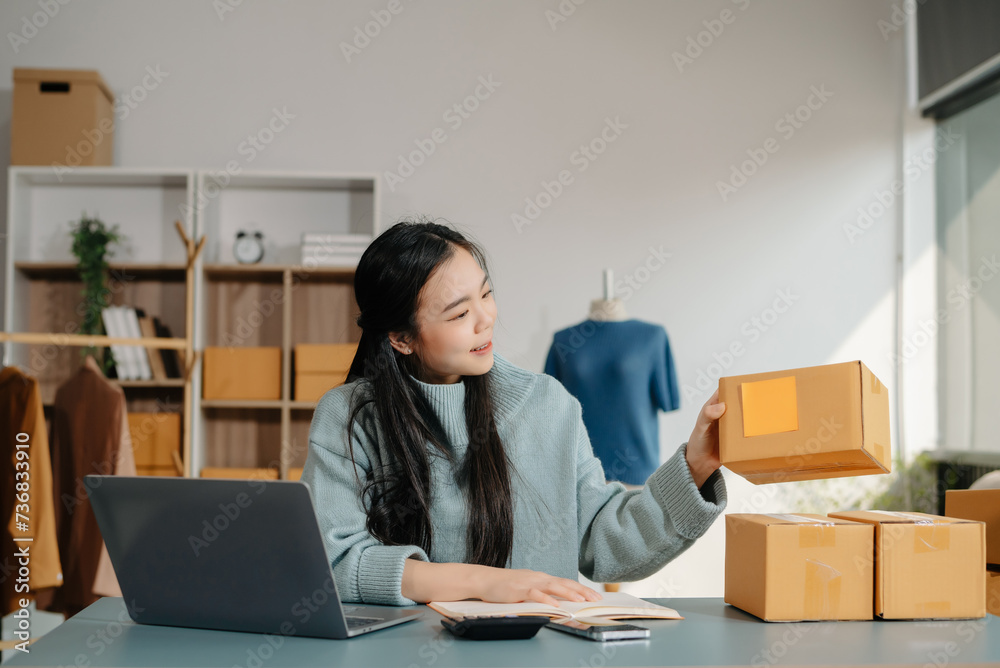 Young Asian women selling clothes on video streaming.Startup small business SME, using smartphone or tablet taking receive and checking Young Asian women selling clothes on video streaming.Startup small business SME, using smartphone or tablet taking receive and checking