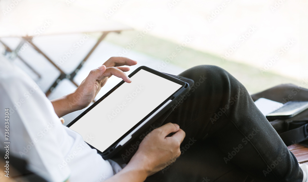 A man sitting outdoor relaxing and using tablet computer
