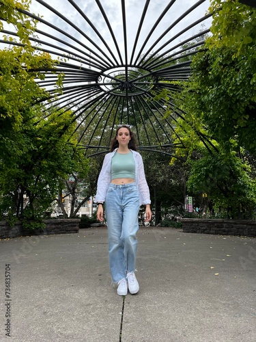 Young Lady Walking Towards the Camera Surrounded by an Outside Garden. Modelling in Jeans and White Blouse