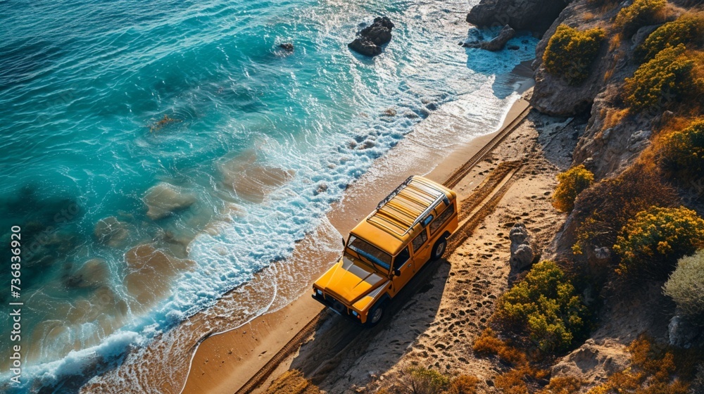 Overhead view of a new heavy car navigating a sandy beach, waves crashing in the background.