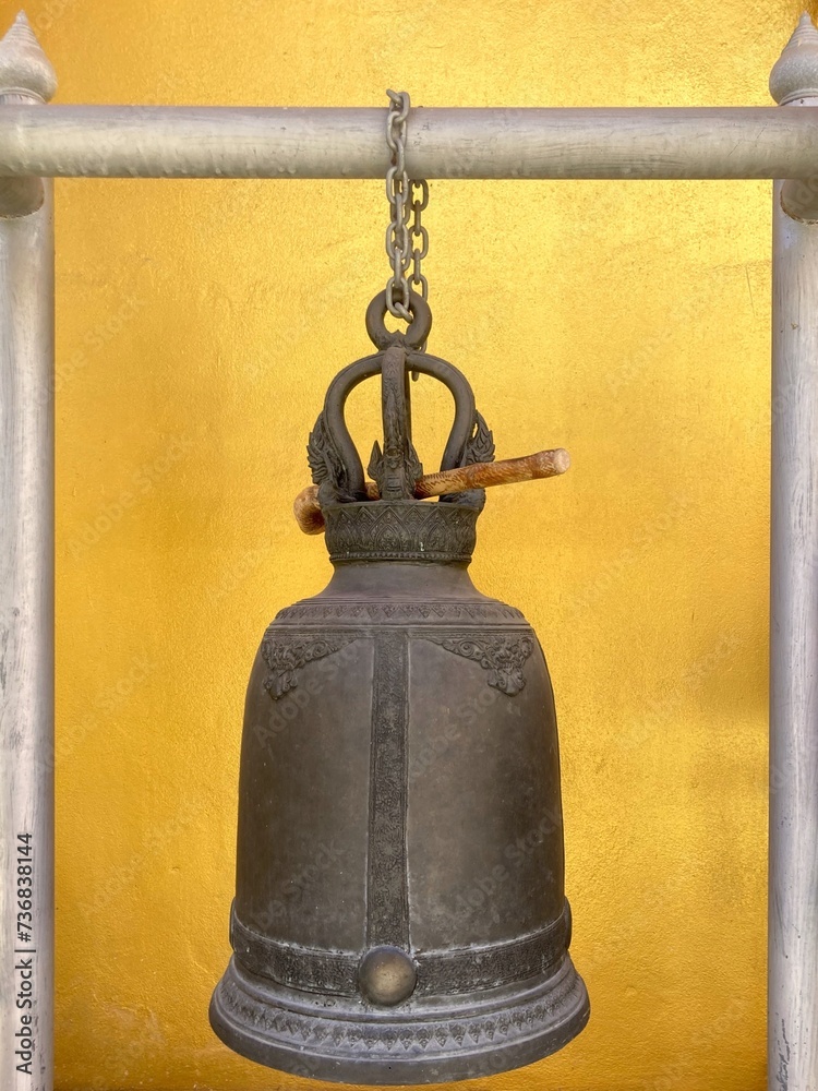 Obraz premium Old hanging bell with bright yellow wall background in temple, Knock for hope, fate, luck in Thailand