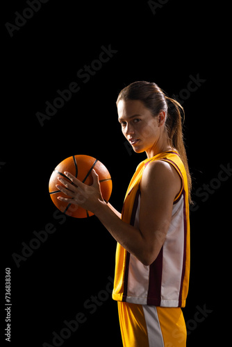 Young Caucasian female basketball player poses confidently in basketball attire, with copy space on 