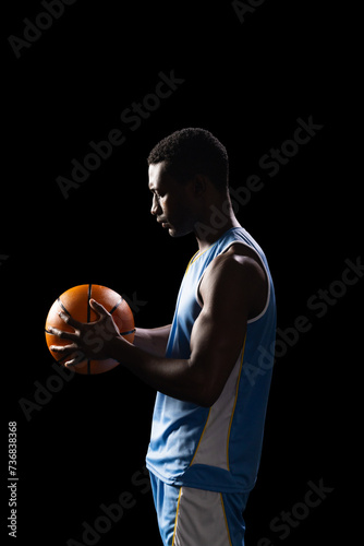African American man holding a basketball on a black background