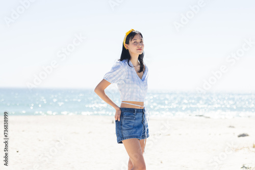 Young biracial woman stands confidently on a sunny beach