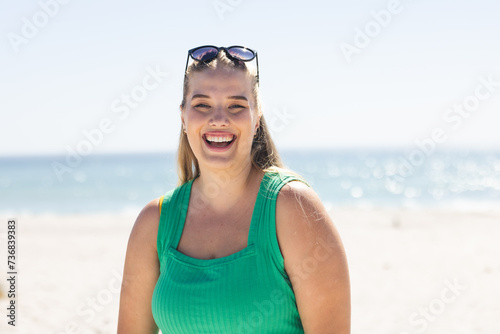 Young plus size Caucasian woman smiles brightly at the beach