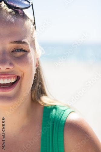 A young plus size Caucasian woman smiles brightly at the beach, with copy space unaltered