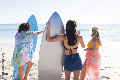 Young biracial and Caucasian women stand by the ocean