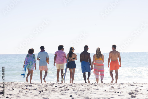 A diverse group of friends enjoys a sunny day at the beach with copy space