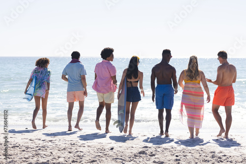 A diverse group of friends enjoys a day at the beach, creating a vibrant outdoor scene by the ocean