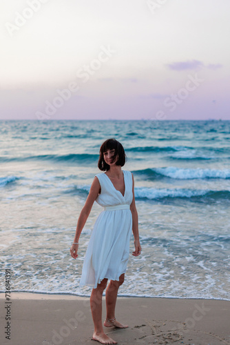 Happy traveler girl in a white summer dress enjoying a tropical paradise beach with turquoise sea.
