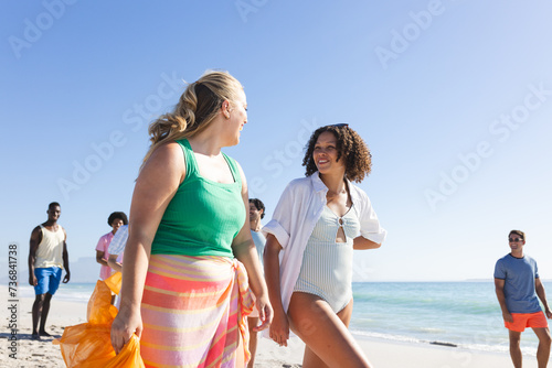 Diverse friends enjoy a sunny day at the beach collecting trash