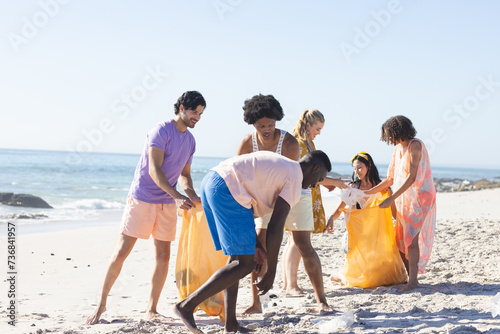 Diverse group enjoys a beach cleanup, collecting trash