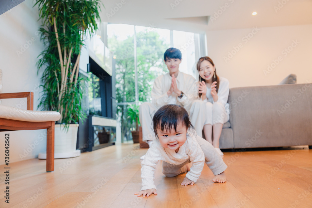 ハイハイをする赤ちゃんと子供の成長を見守る両親 ハイハイをする赤ちゃんと子供の成長を見守る両親