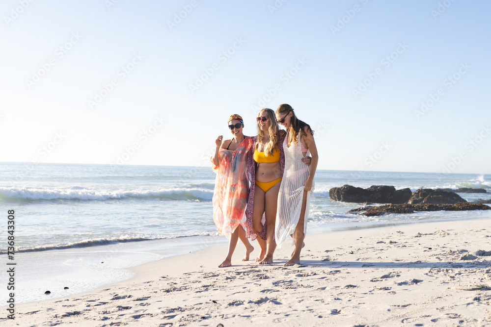 Three young women enjoy a sunny beach day, with copy space