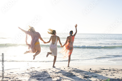 Three young women enjoy a carefree jump on a sunny beach