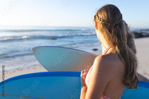 Young Caucasian woman holds a surfboard on the beach, with copy space