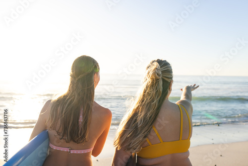 Two young Caucasian women gaze at the ocean, with copy space