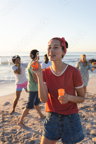 Young Caucasian woman enjoys blowing bubbles on the beach