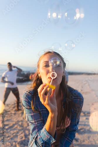 Young Caucasian woman blows bubbles on a sunny beach