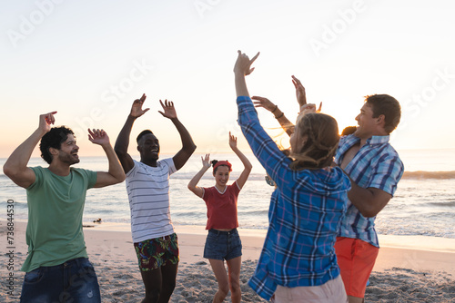 Diverse group of friends enjoy a beach sunset, with copy space