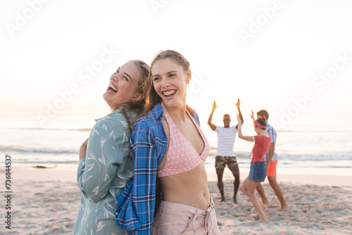 Friends enjoy a vibrant beach sunset, with copy space