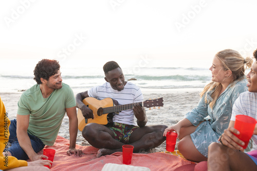 Diverse friends enjoy a beach gathering, having a party, with copy space