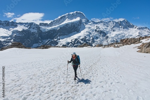 Middle-aged woman hiking solo in snowy terrain amidst icy, rocky mountains