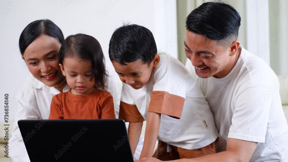 Happy Asian young family with little kids using laptop together in a living room Happy Asian young family with little kids using laptop together in a living room