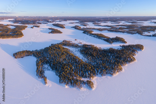Aerial view over snow covered winter landscape with frozen lakes and boreal forest in northeast Finland 