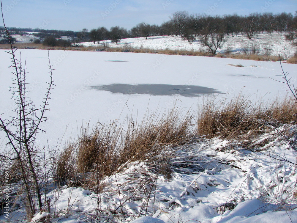 A view from the shore of the unfrozen areas at the depth of the steppe lake, which warn of the danger of those wishing to skate. A view from the shore of the unfrozen areas at the depth of the steppe lake, which warn of the danger of those wishing to skate.