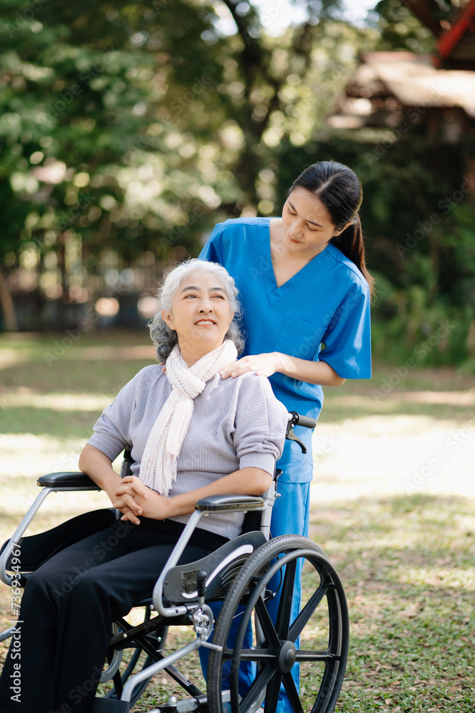 Elderly asian senior woman on wheelchair with Asian careful caregiver and encourage patient, walking in garden. with care from a caregiver and senior health insurance...
