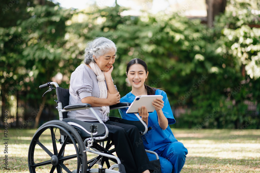 Elderly asian senior woman on wheelchair with Asian careful caregiver and encourage patient, walking in garden. with care from a caregiver and senior health insurance...