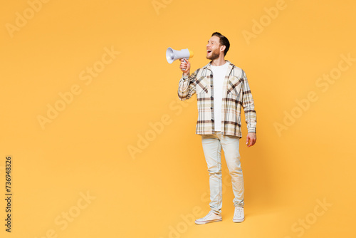 Full body young man he wears brown shirt casual clothes hold in hand megaphone scream announces discounts sale Hurry up isolated on plain yellow orange background studio portrait. Lifestyle concept.