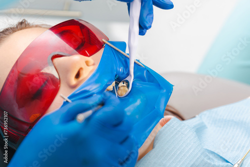 Close up shot of a female patient at the dentist wearing latex dental dam and protection glasses. photo