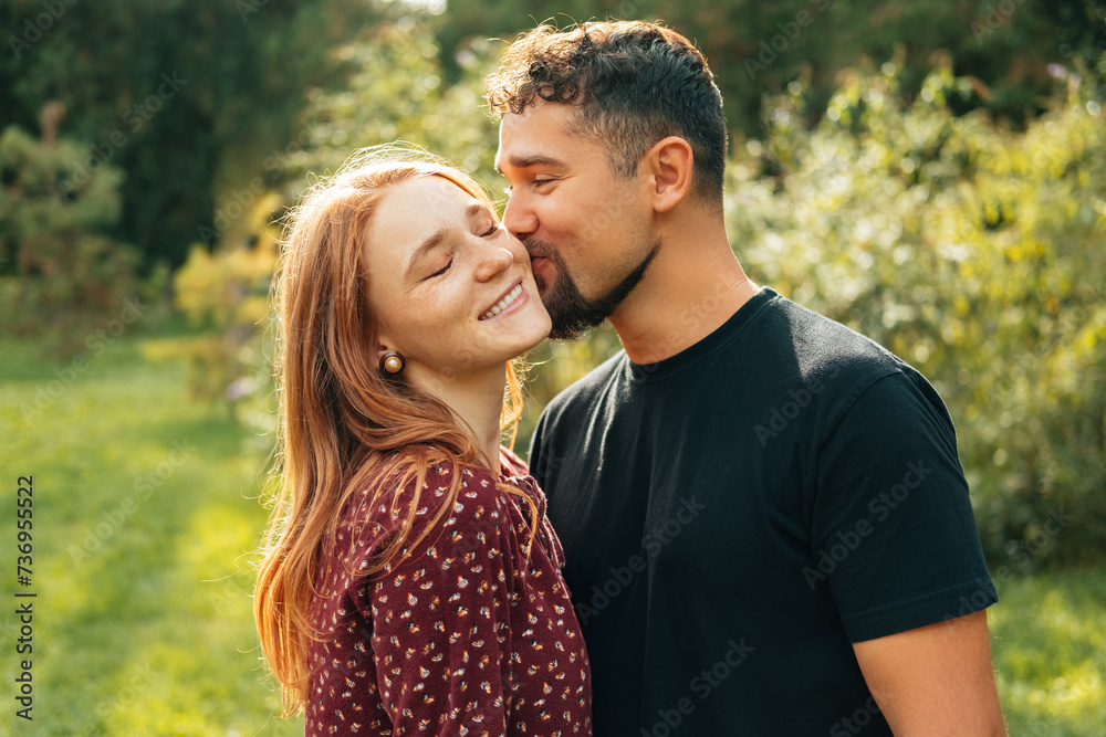 Warm shot of a beautiful happy couple where man kisses his woman while walking in park. Warm shot of a beautiful happy couple where man kisses his woman while walking in park.