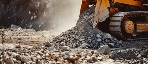 A bulldozer is moving rocks to create a pile at a construction site, preparing the area for the building of a new house or road
