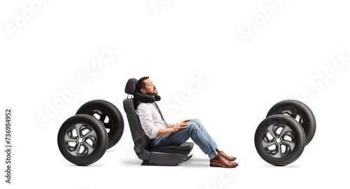 Man in a car seat on four tires with a travel pillow around neck