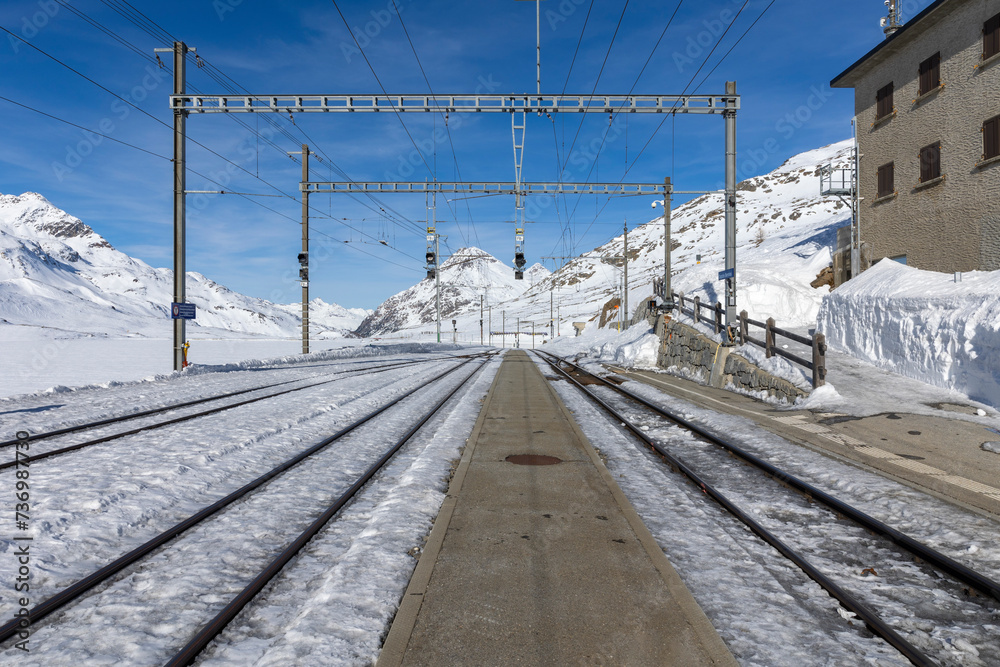 Train station on the Bernina Pass in Switzerland. Front view from the railway platform and tracks appearing from the snow.