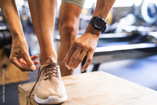 Fit person tying shoe laces before a workout at the gym photo