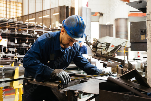 Factory worker cutting iron rod in workshop