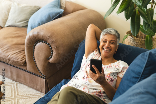 A mature biracial woman enjoys a relaxing moment at home, with copy space