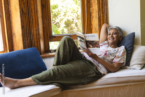 A mature biracial woman enjoys reading at home photo