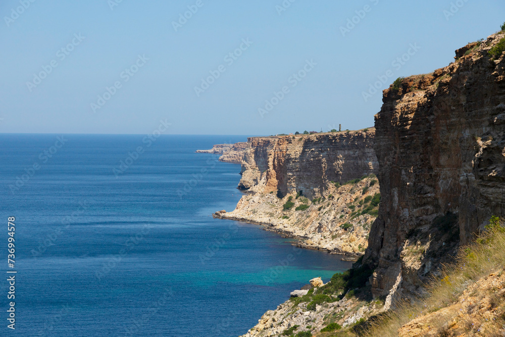 Steep banks, cliffs over the blue sea. The rocks are located on the right. Landscape