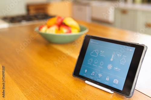 A tablet displaying smart home controls sits on a kitchen counter photo