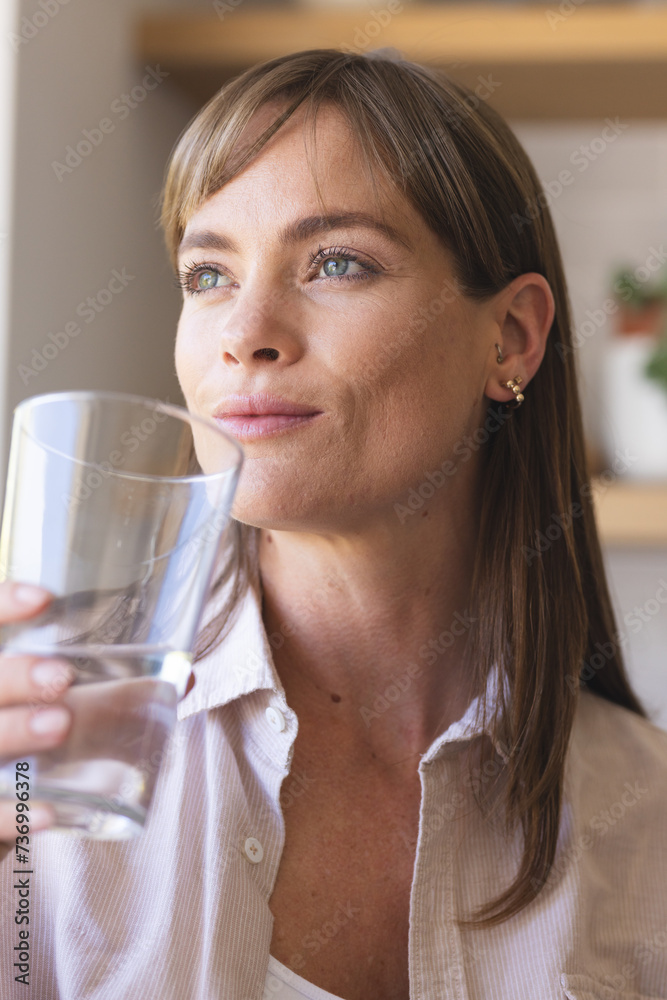 A middle-aged Caucasian woman is drinking water from a clear glass A middle-aged Caucasian woman is drinking water from a clear glass