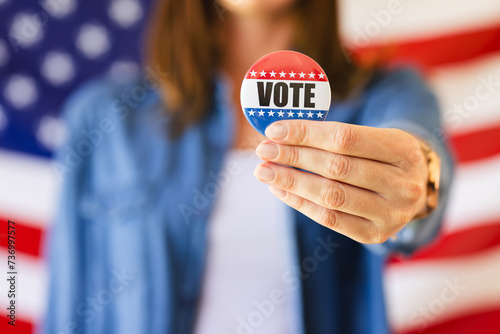 A caucasian woman is holding out a vote badge towards the camera, with copy space unaltered photo