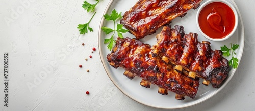 a white plate topped with grilled pork ribs and ketchup . High quality photo