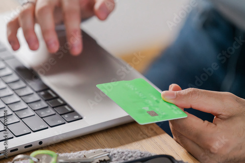 hand placing a credit card on a laptop trackpad, symbolizing a secure online transaction from home photo