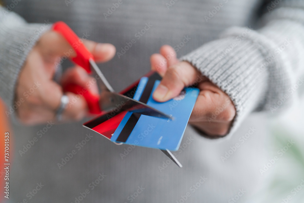 © Studio Marmellata - A man's hands cutting a blue credit card with red scissors, symbolizing financial management or the end of a credit account. The decisive cut reflects personal finance decisions © Studio Marmellata - A man's hands cutting a blue credit card with red scissors, symbolizing financial management or the end of a credit account. The decisive cut reflects personal finance decisions